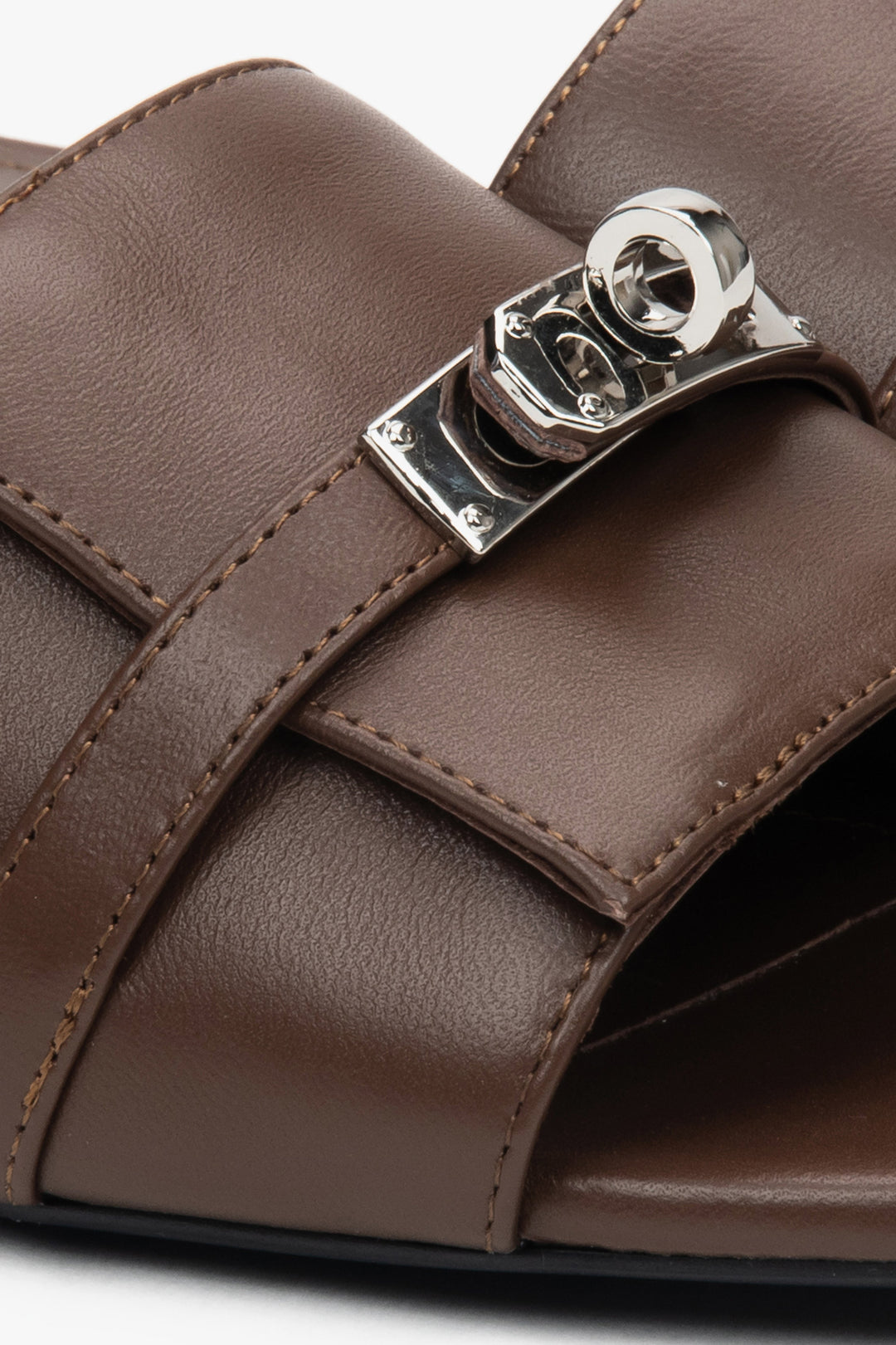 Dark brown flat-heeled slides with a silver embellishment from Estro – a blend of comfort, subtle elegance, and versatile design, close-up on details.