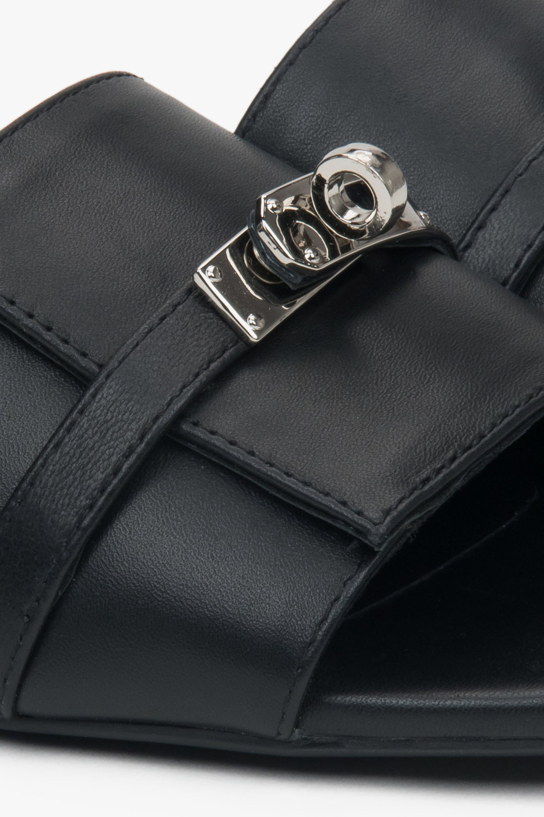 Black flat-heeled slides with a silver embellishment from Estro – a blend of comfort, subtle elegance, and versatile design, close-up on details.