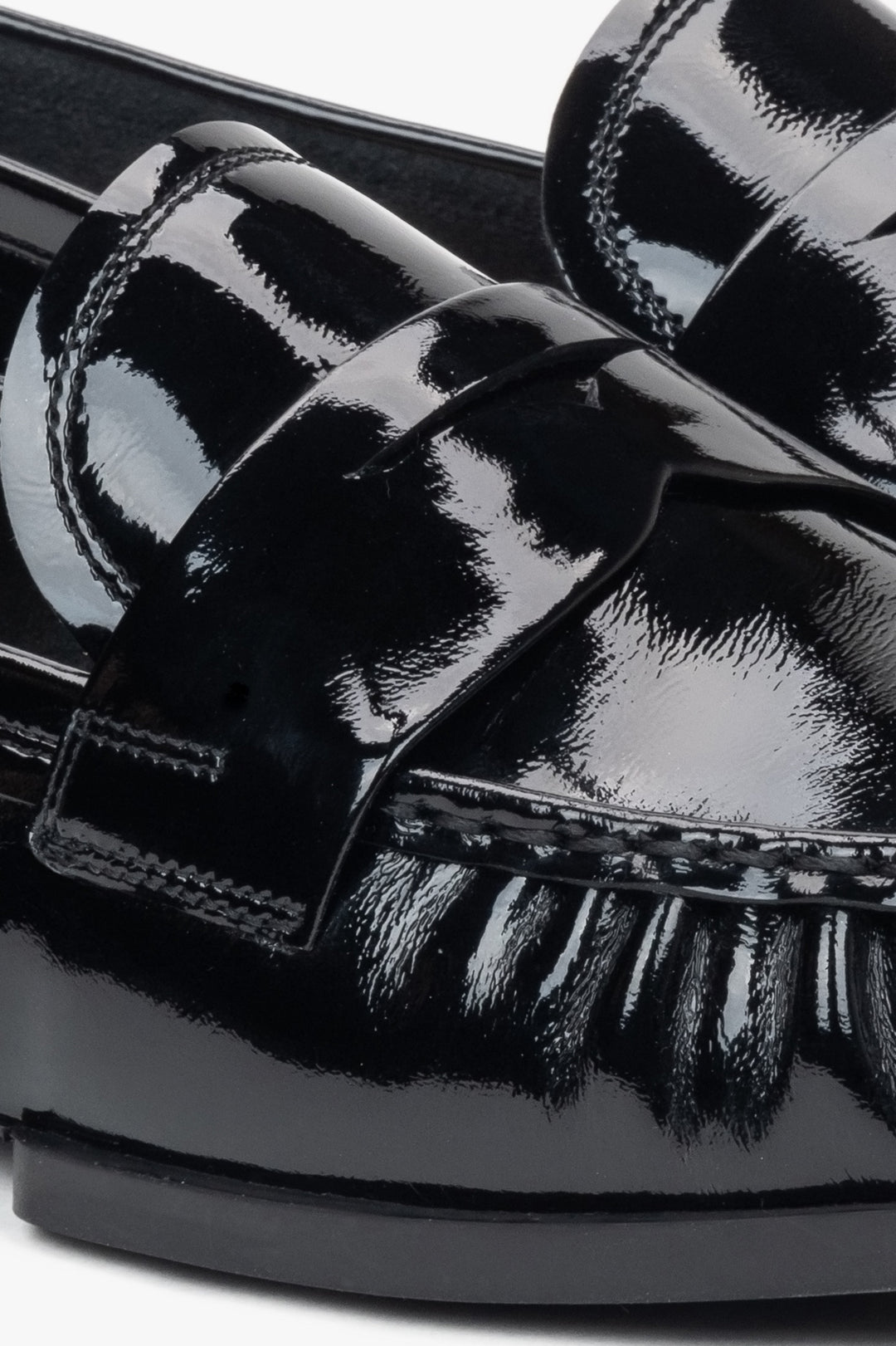 Stylish women's loafers made of black patent genuine leather – close-up on the details.