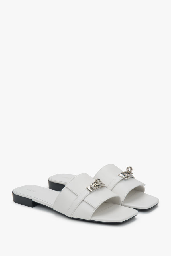 Elegant white Estro women's slide sandals, adorned with a silver embellishment, perfect for everyday wear, featuring a comfortable flat heel.
