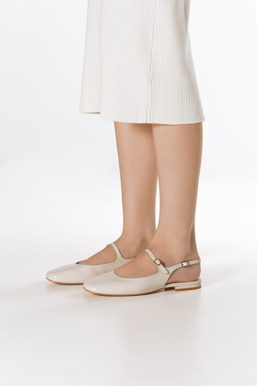 Women's light beige patent leather flats with slingback strap - presentation of the shoes on the foot.