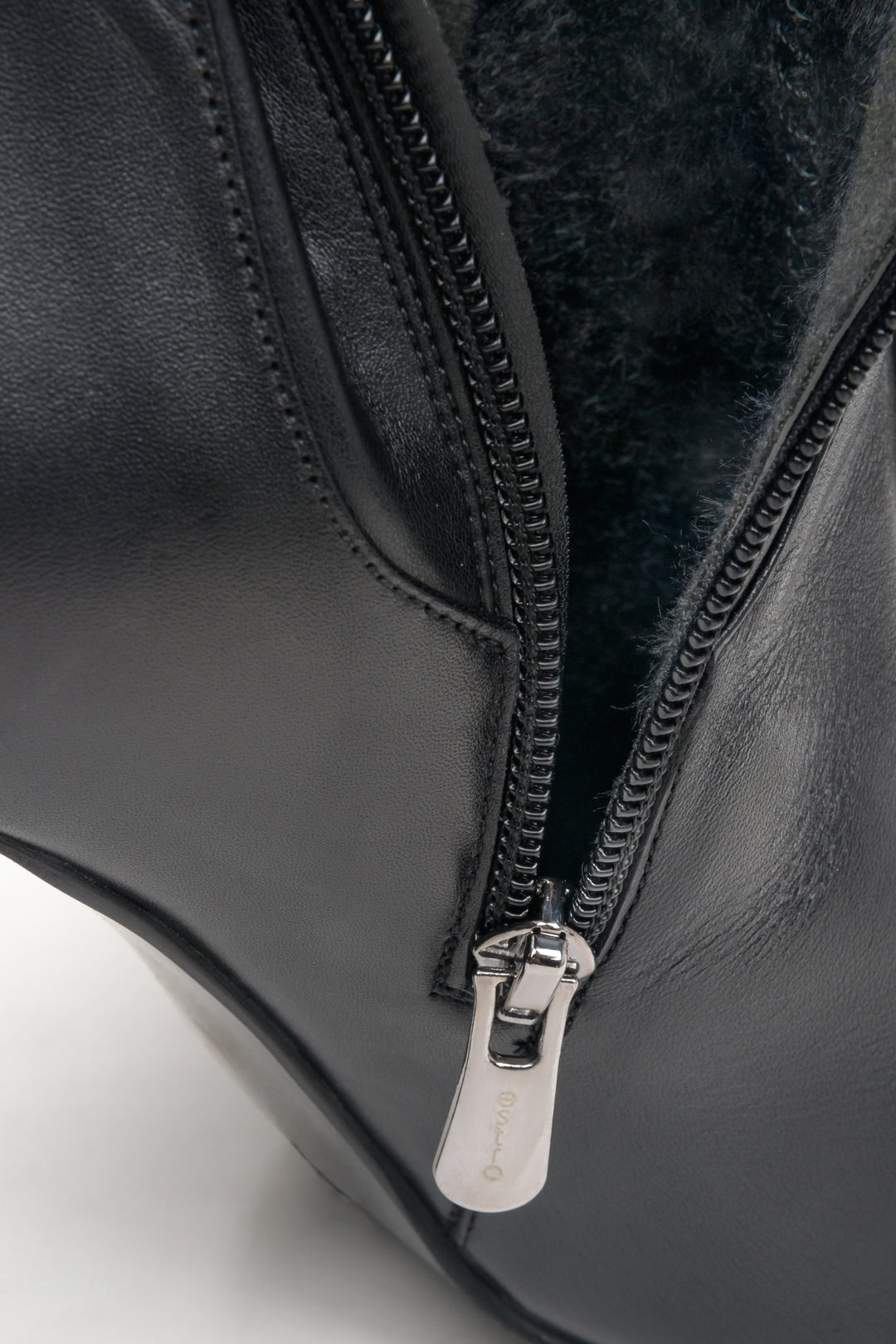 Black leather knee-high heeled boots - a close-up on fastening.