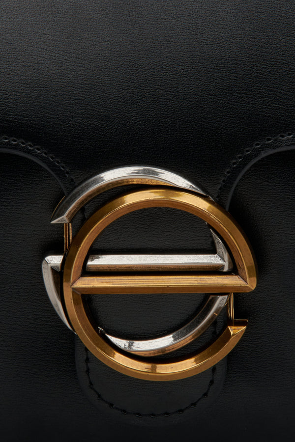 Women's small black handbag with gold hardware made of leather by Estro - close-up on a logo.