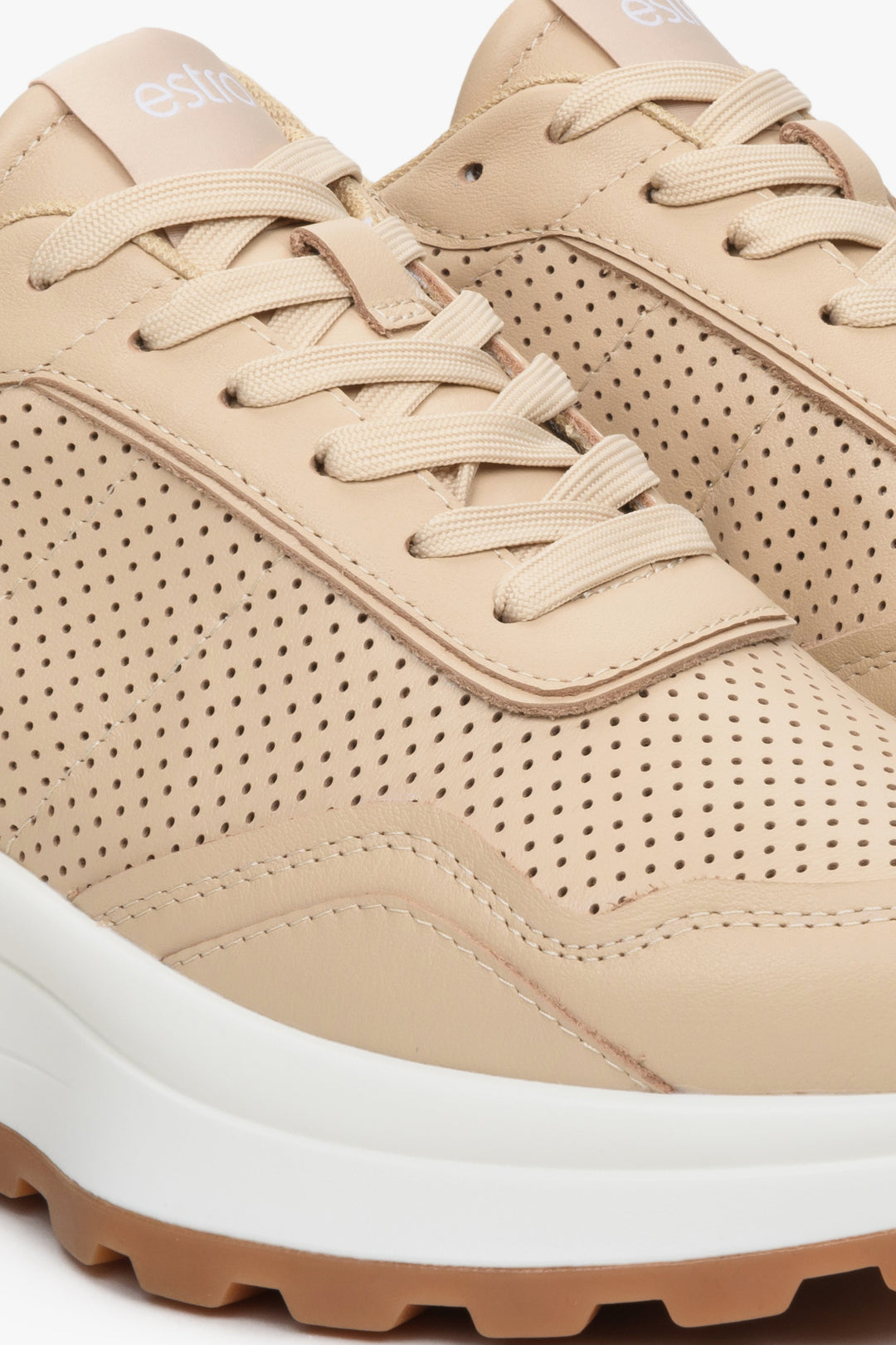 Women's beige leather sneakers with perforation - close-up of the stitching pattern.