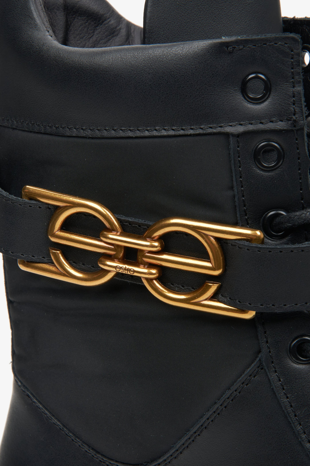 Elegant black women's ankle boots natural leather with a golden ornament - close-up on details.