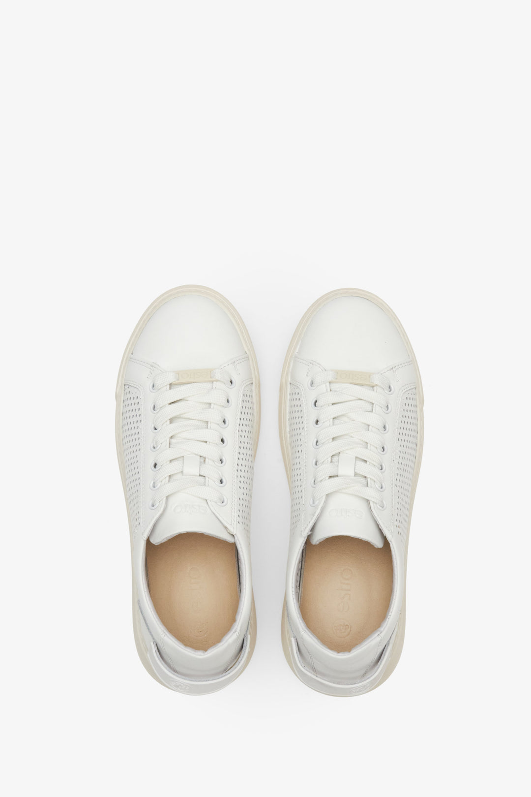Women's white leather sneakers with perforation - presentation of the footwear from above.