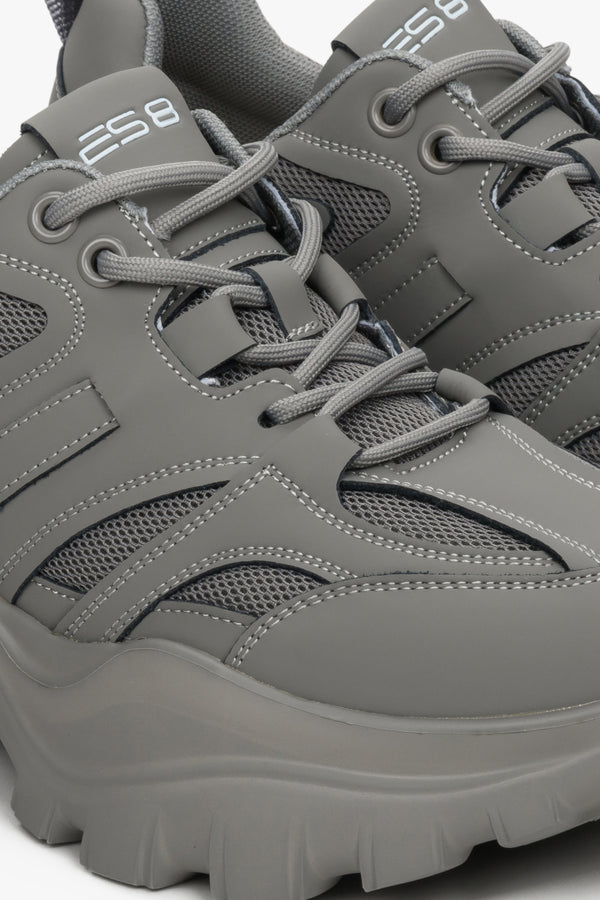 Women's grey sneakers made of genuine leather - close-up of the stitching system and shoe details.