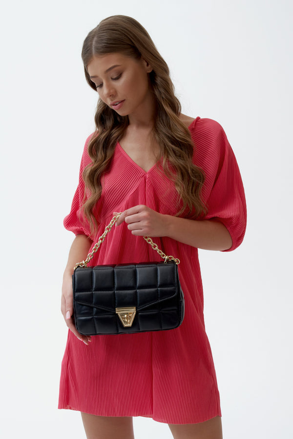 Elegant black leather women's handbag by Estro with a chain strap and quilting - presentation on a model.