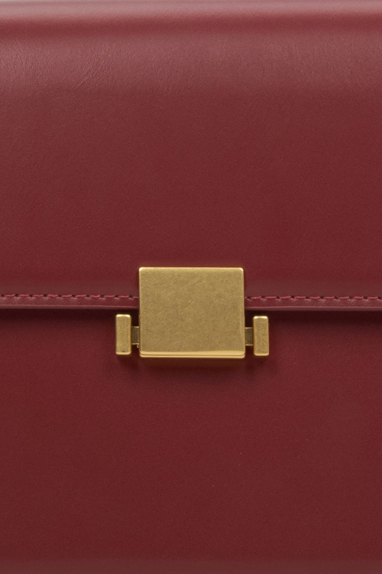 Women's burgundy handbag - close-up of the snap closure.