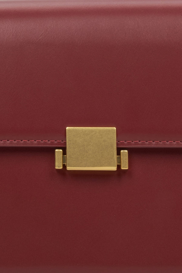 Women's burgundy handbag - close-up of the snap closure.