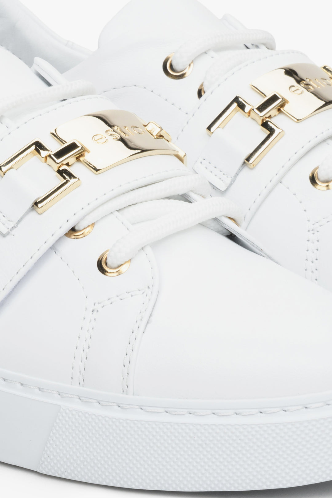 Women's white leather sneakers with a gold embellishment - close-up on the details.
