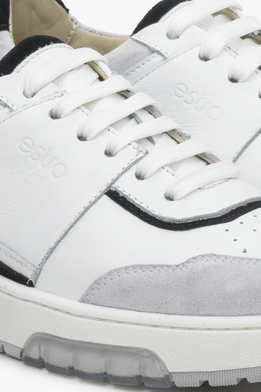 Women's sneakers made of genuine leather and suede in grey, black and white - close-up on the details.