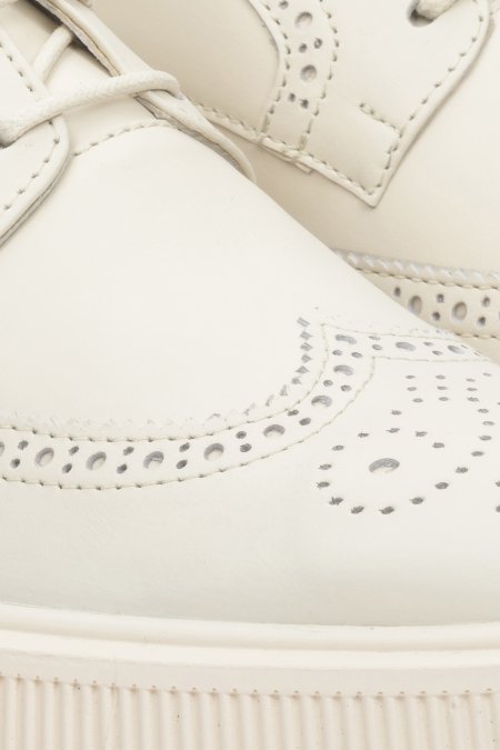 Women's beige leather shoes made from genuine leather - close-up on details with perforation.
