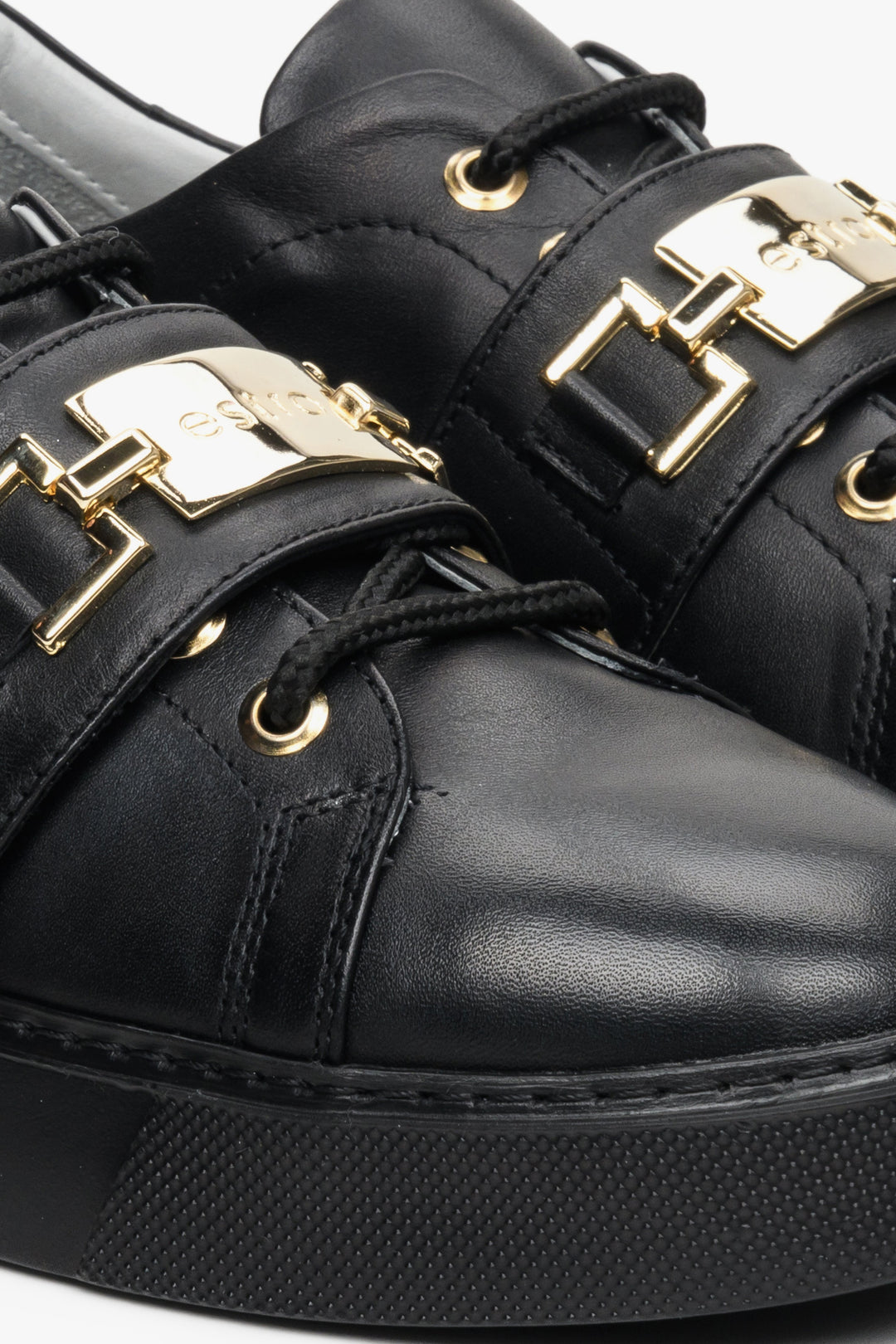 Women's black leather sneakers with a gold embellishment - close-up on the details.