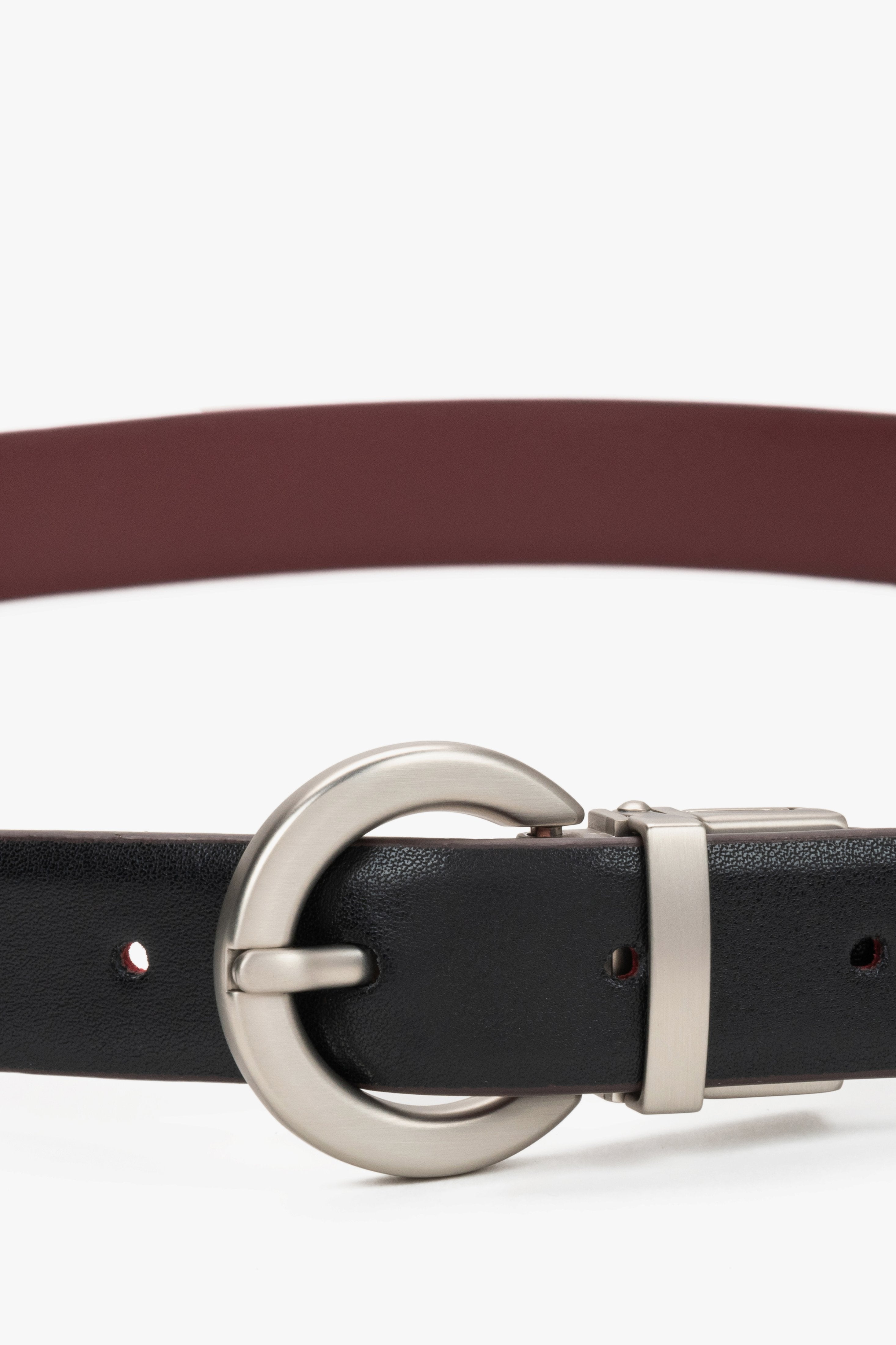Women's leather belt in black and burgundy with a polished round silver buckle, laid flat.