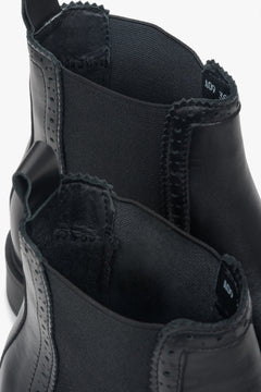 A close-up view of the perforation detail on a pair of women's black Italian leather Chelsea boots.