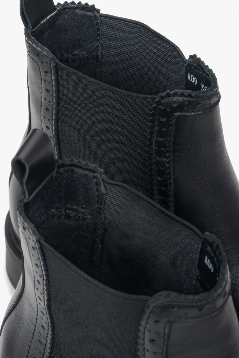 A close-up view of the perforation detail on a pair of women's black Italian leather Chelsea boots.
