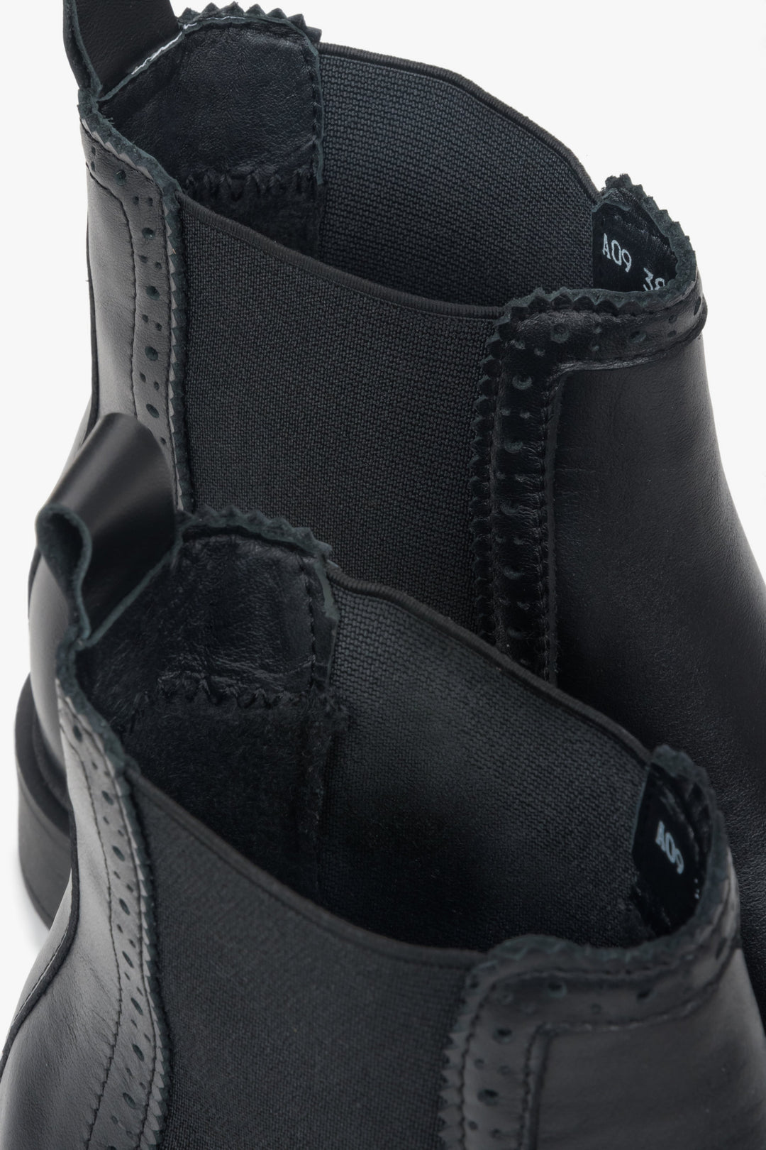 A close-up view of the perforation detail on a pair of women's black Italian leather Chelsea boots.