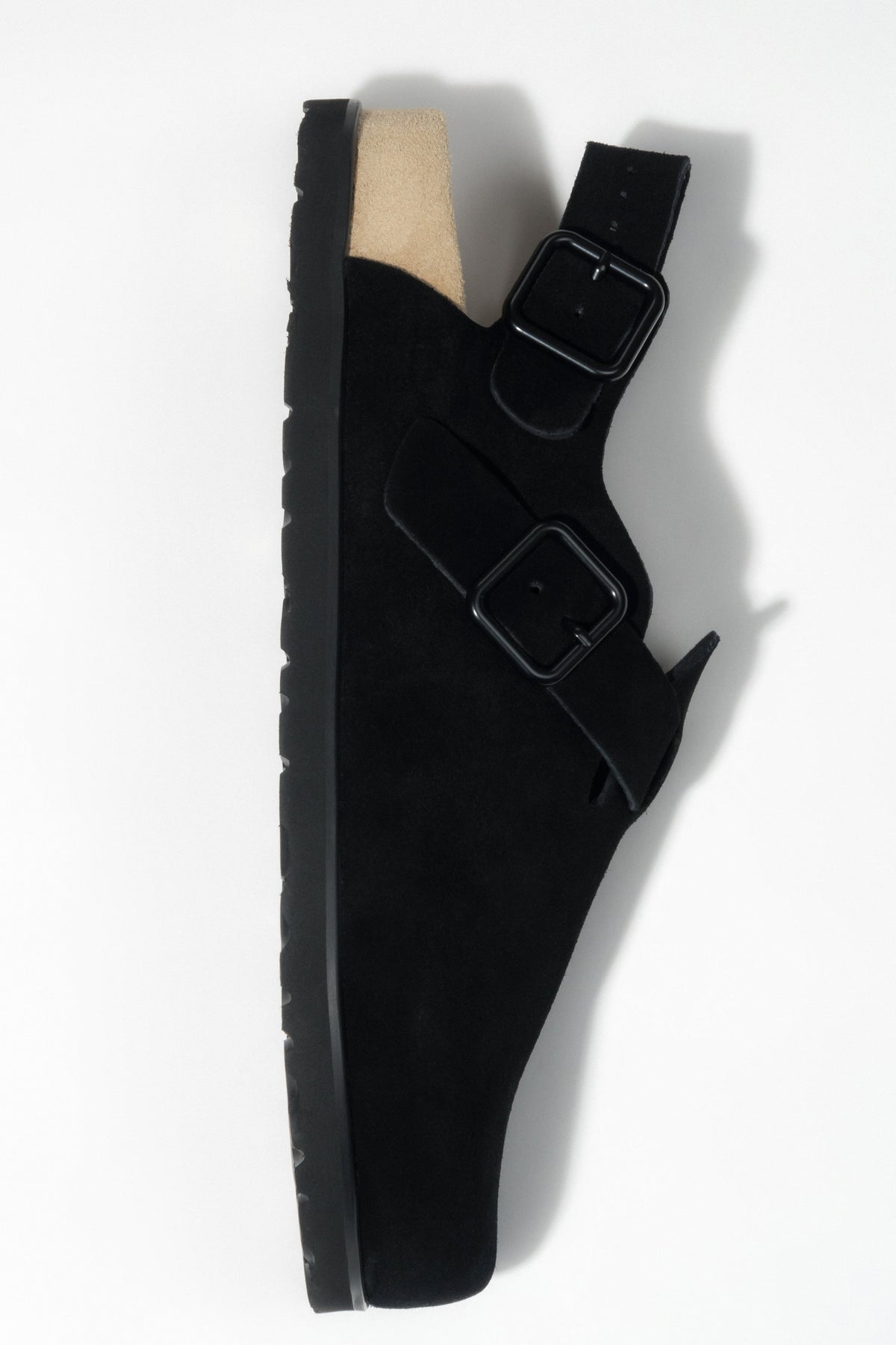 Side profile of a women's black suede clog, highlighting the closed-toe and open-back style.