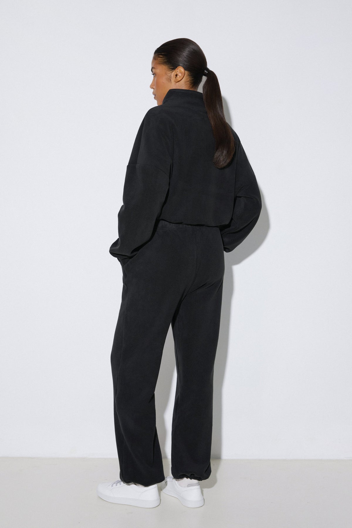 Women's black fleece tracksuit set Estro - back view highlighting the comfortable cut and hooded detail.