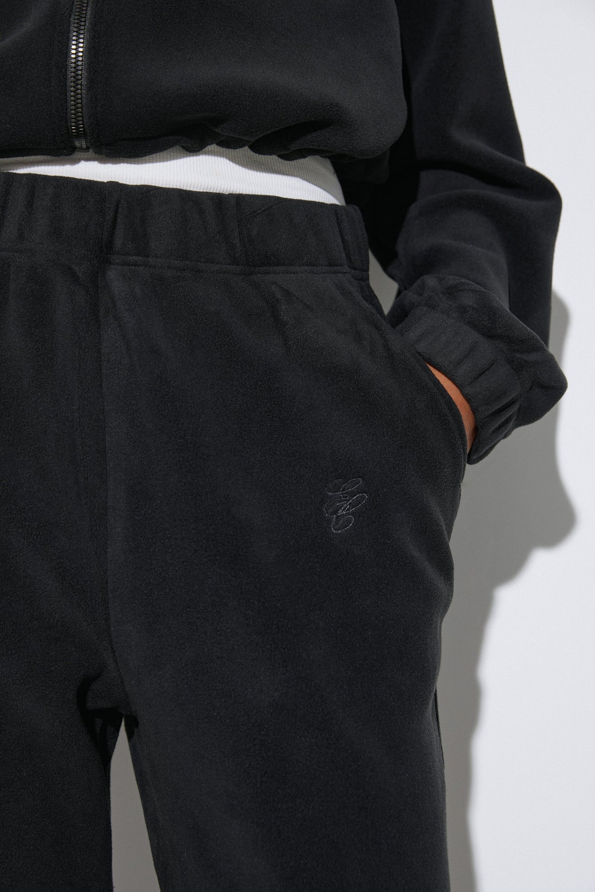 Women's black fleece tracksuit set Estro - close-up view highlighting the cozy fleece texture, hood detailing, and subtle finish.