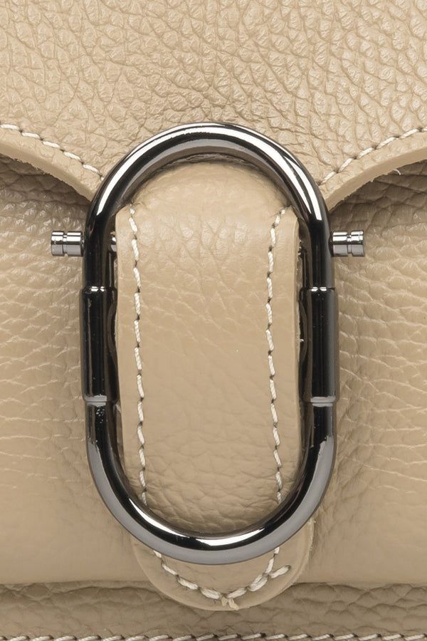 Women's small beige handbag - close-up on the gold embellishmen.