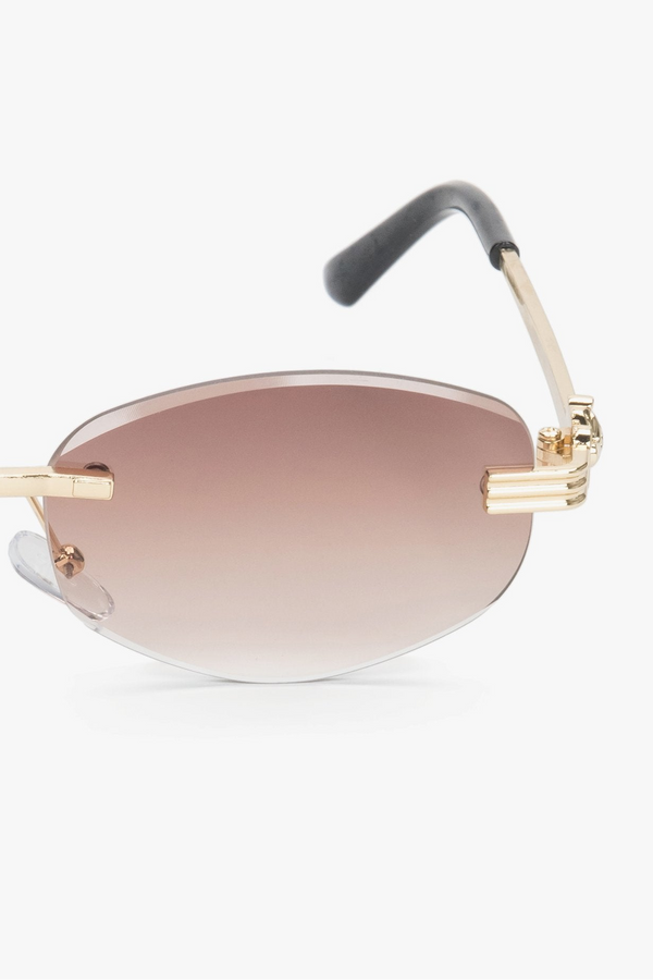 A pair of minimalist, oval sunglasses featuring a frameless design with brown lenses and gold details.