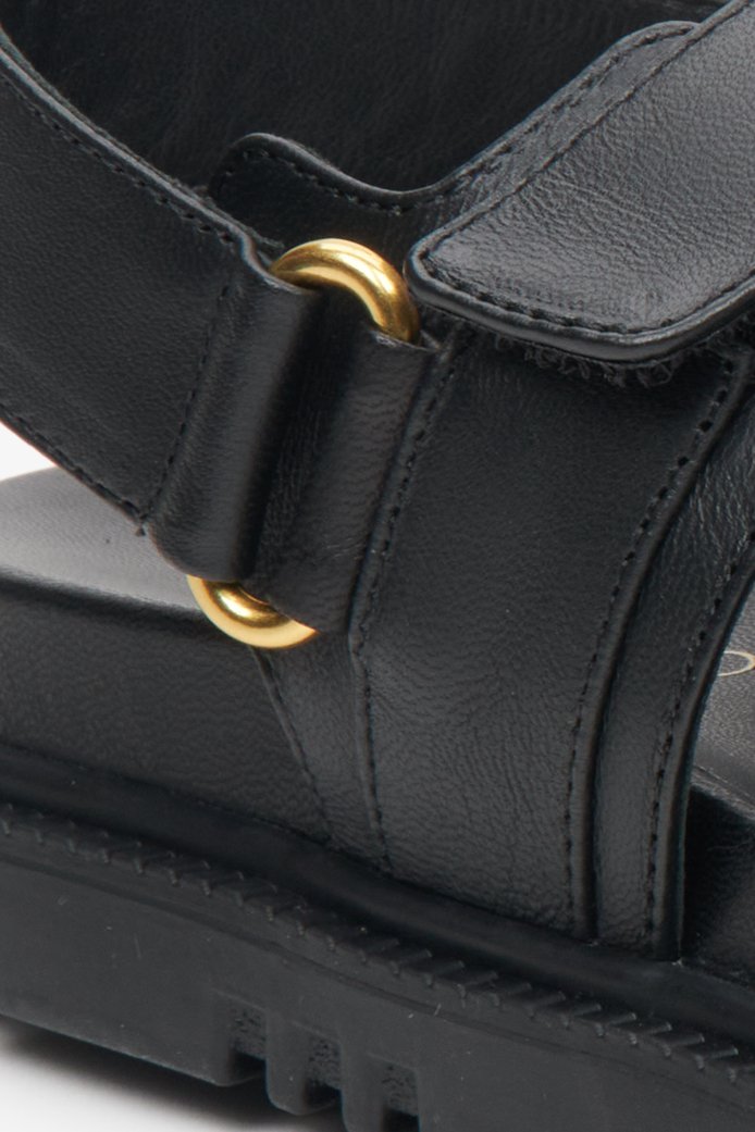 Women's black leather  comfortable sole sandals with golden elements - close-up on the details.