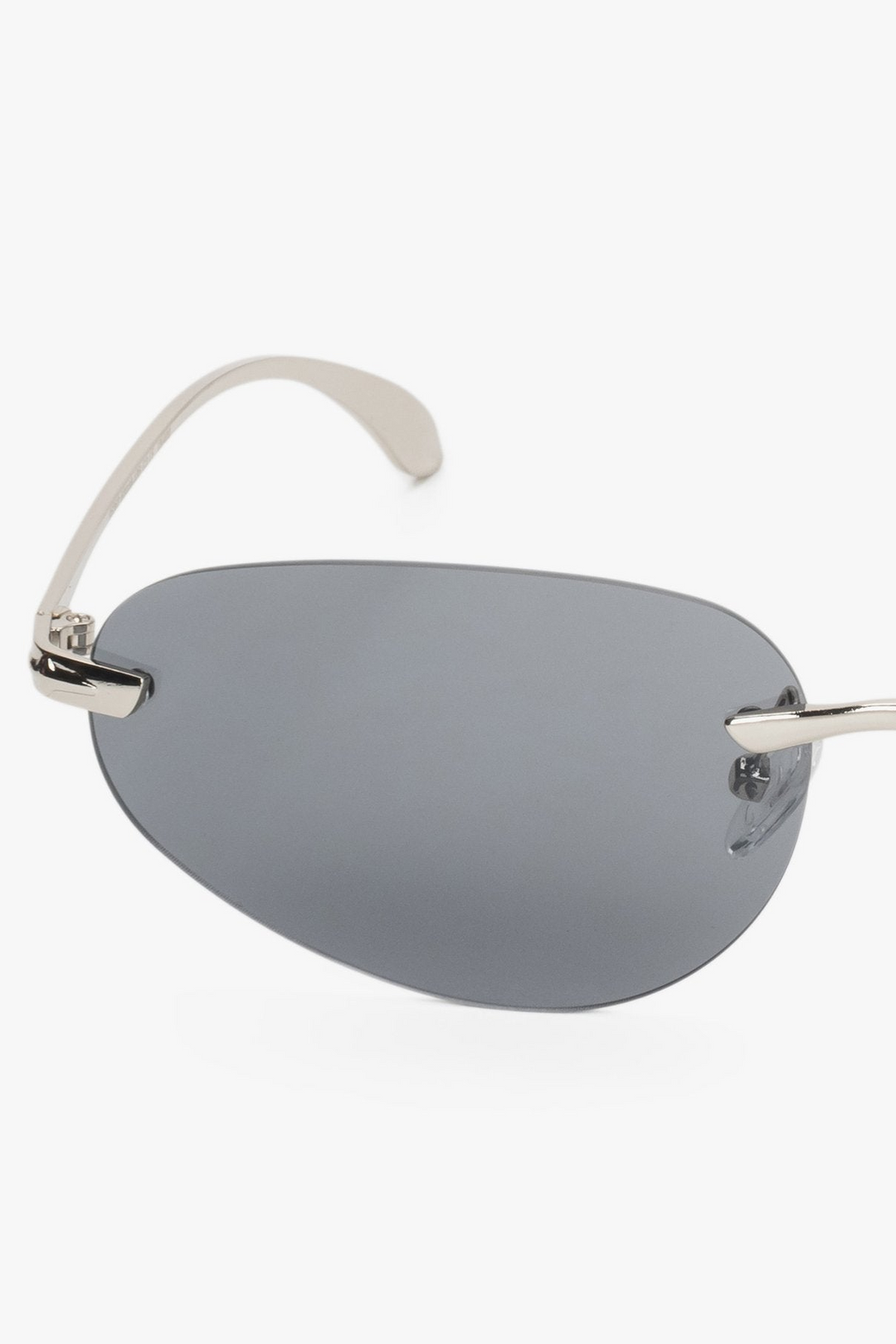 A pair of slim, frameless sunglasses in a dark grey tint - a close-up on details.