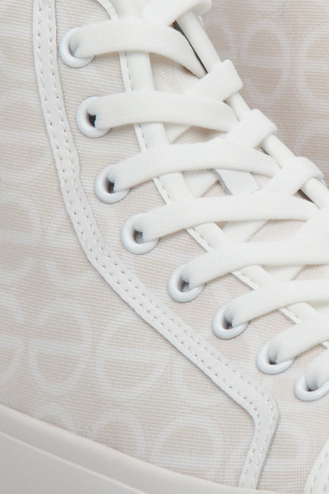 Sporty women's sneakers in beige and white, laced - a close-up on details.