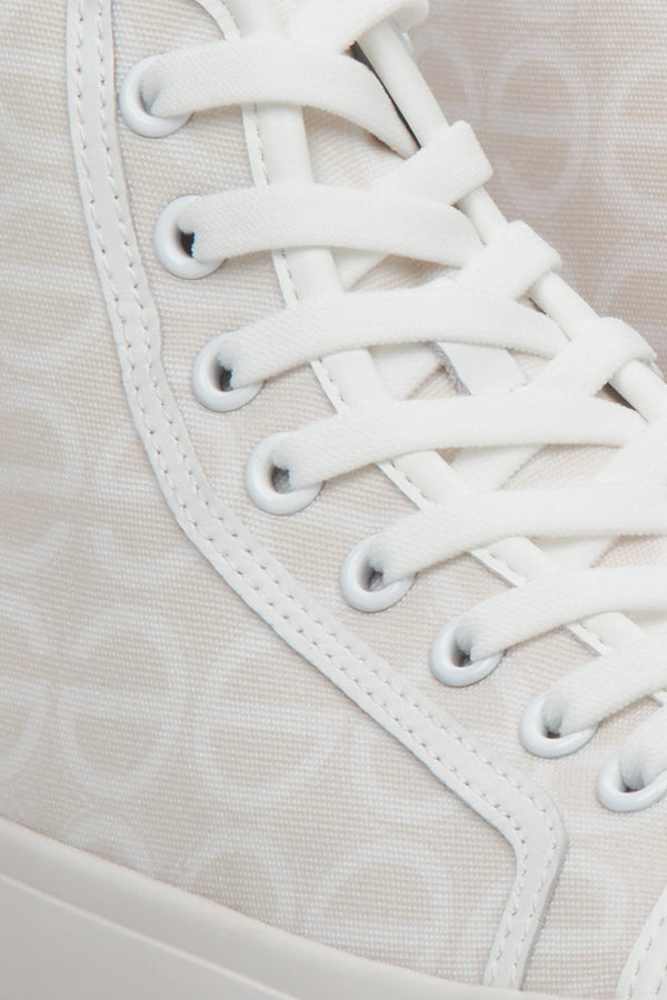 Sporty women's sneakers in beige and white, laced - a close-up on details.