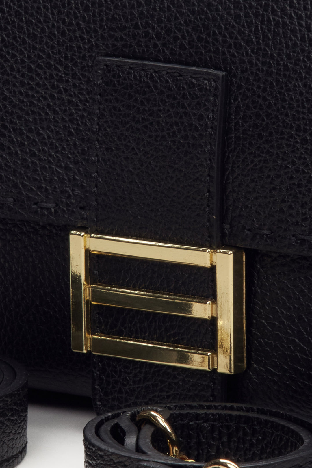 Women's handbag made of Italian genuine black leather with golden hardware - close-up on detail.