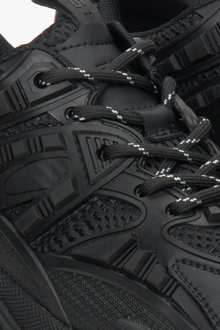 Women's black leather sneakers with laces - close-up on the shoe lacing.