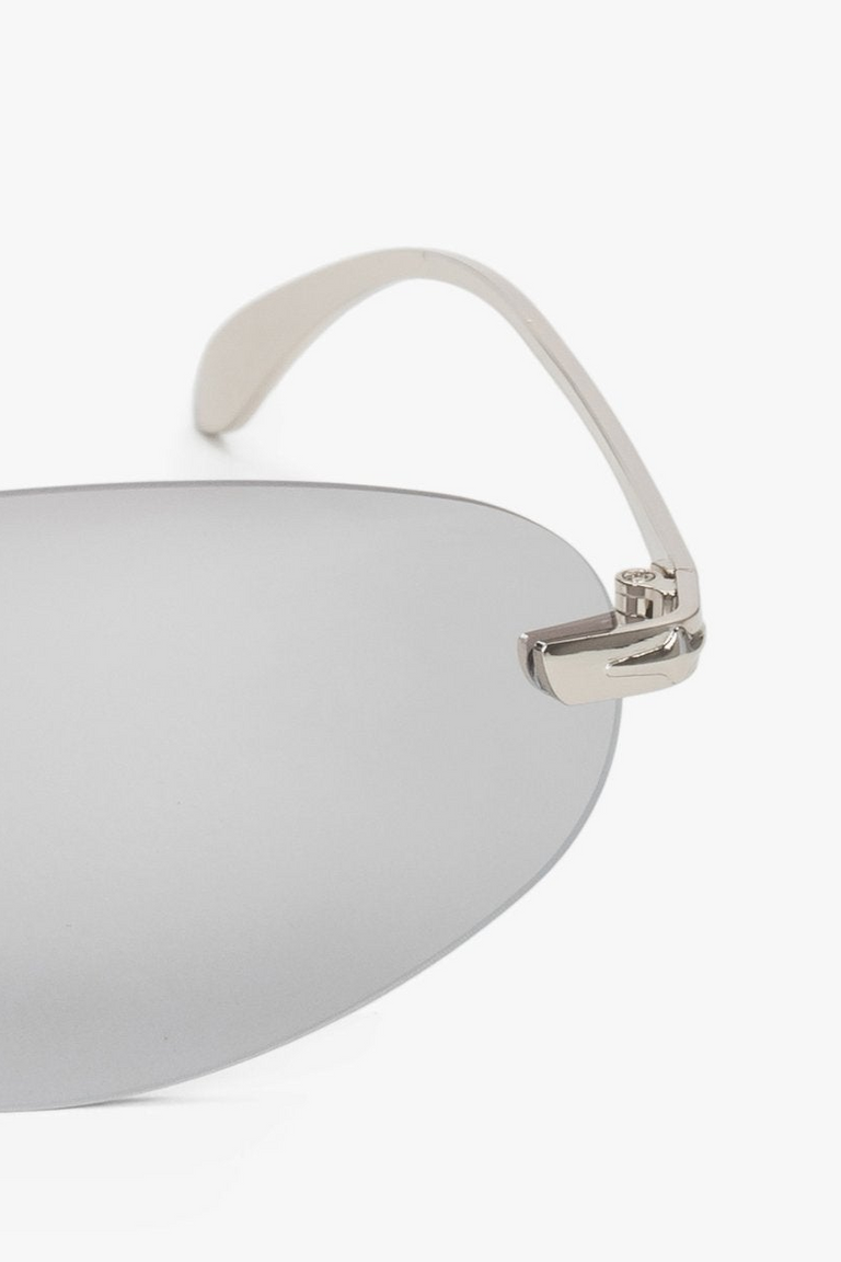 A pair of women's narrow sunglasses with a frameless design and light grey lenses by Estro - a close-up on details.