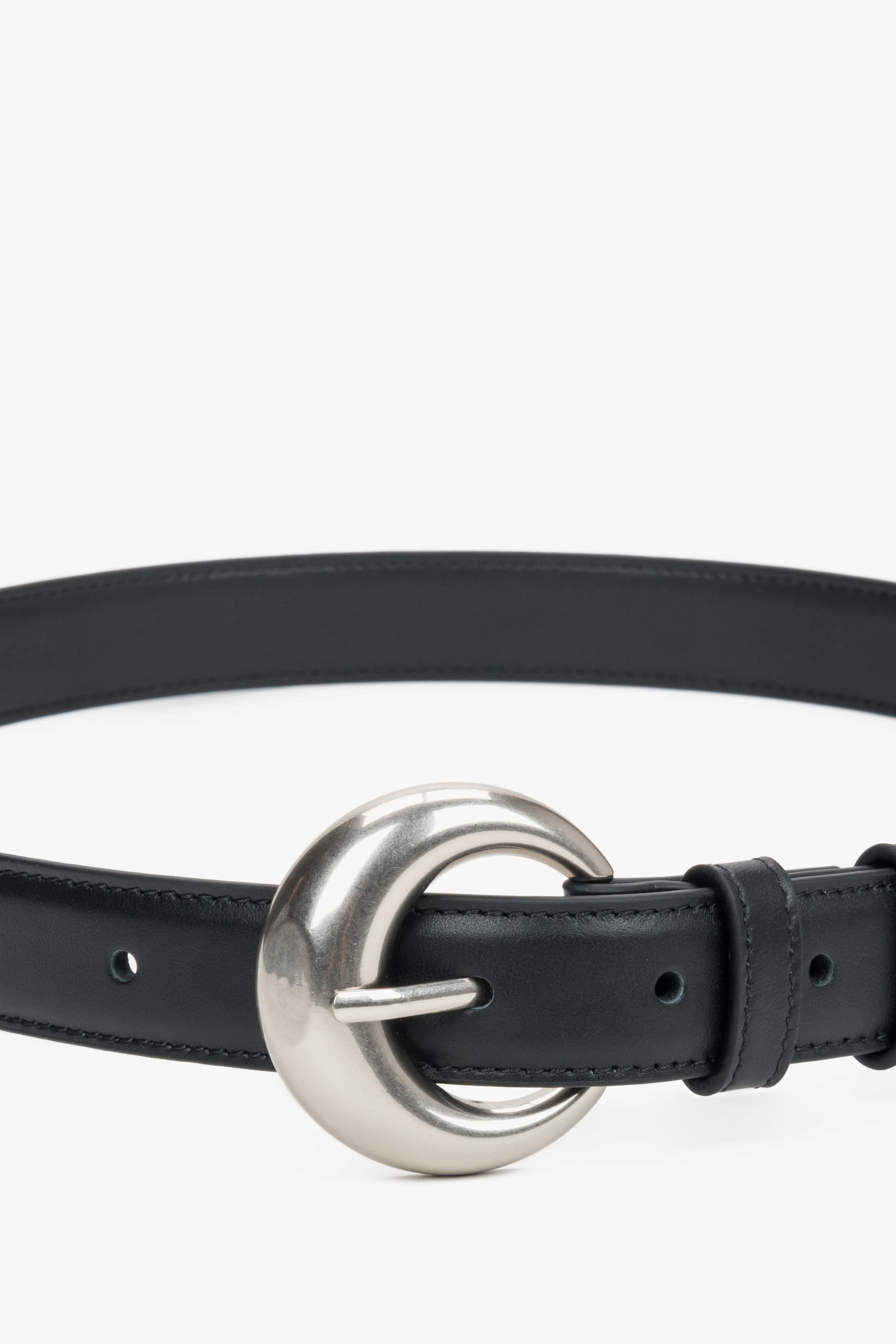 Close-up of the rounded silver buckle on a black belt.