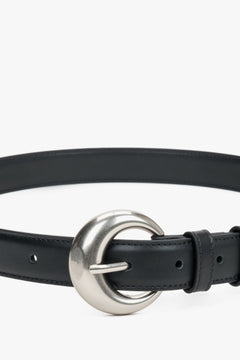 Close-up of the rounded silver buckle on a black belt.