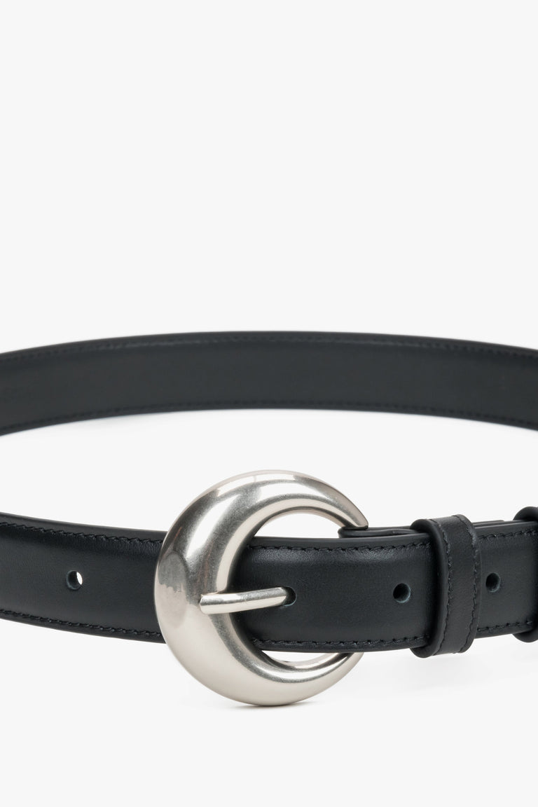 Close-up of the rounded silver buckle on a black belt.