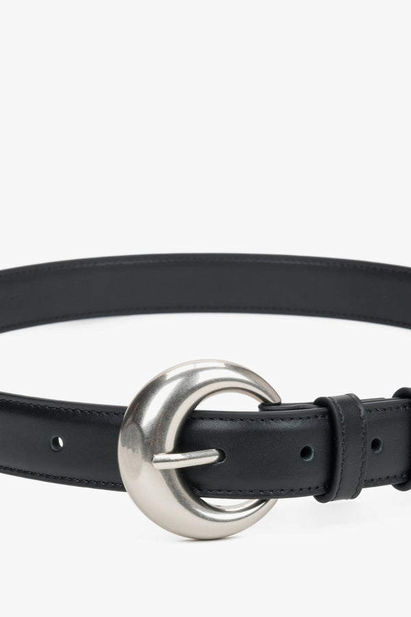 Close-up of the rounded silver buckle on a black belt.
