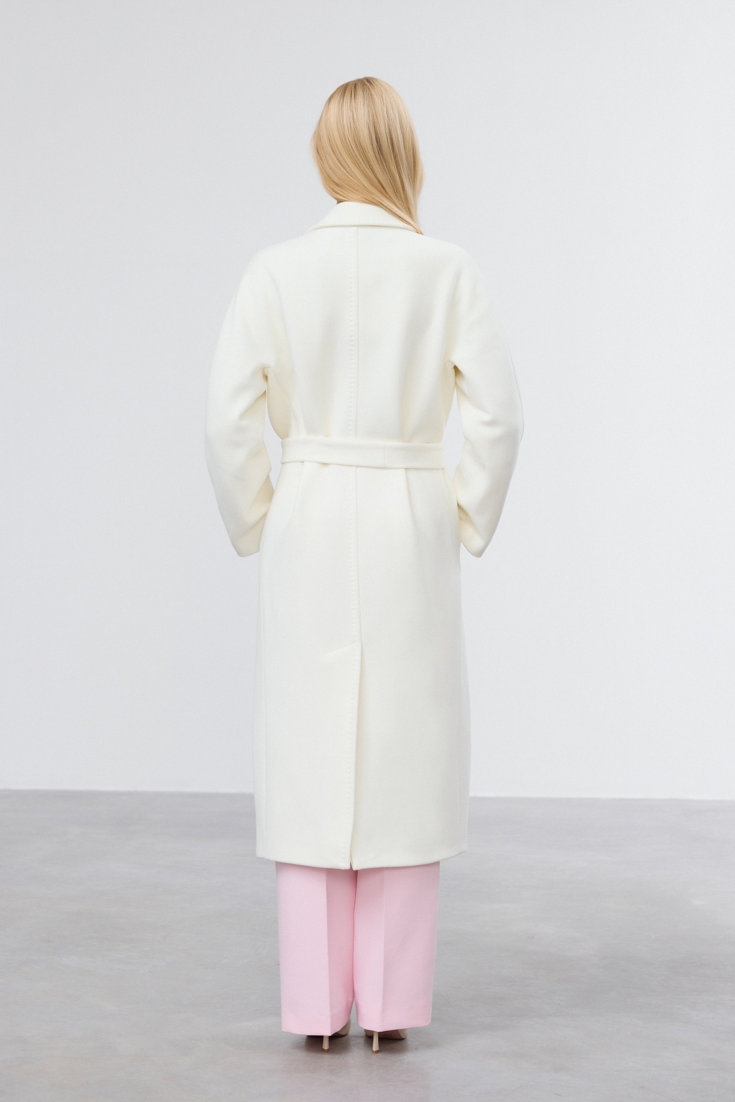Back view of milky beige belted bucket coat.