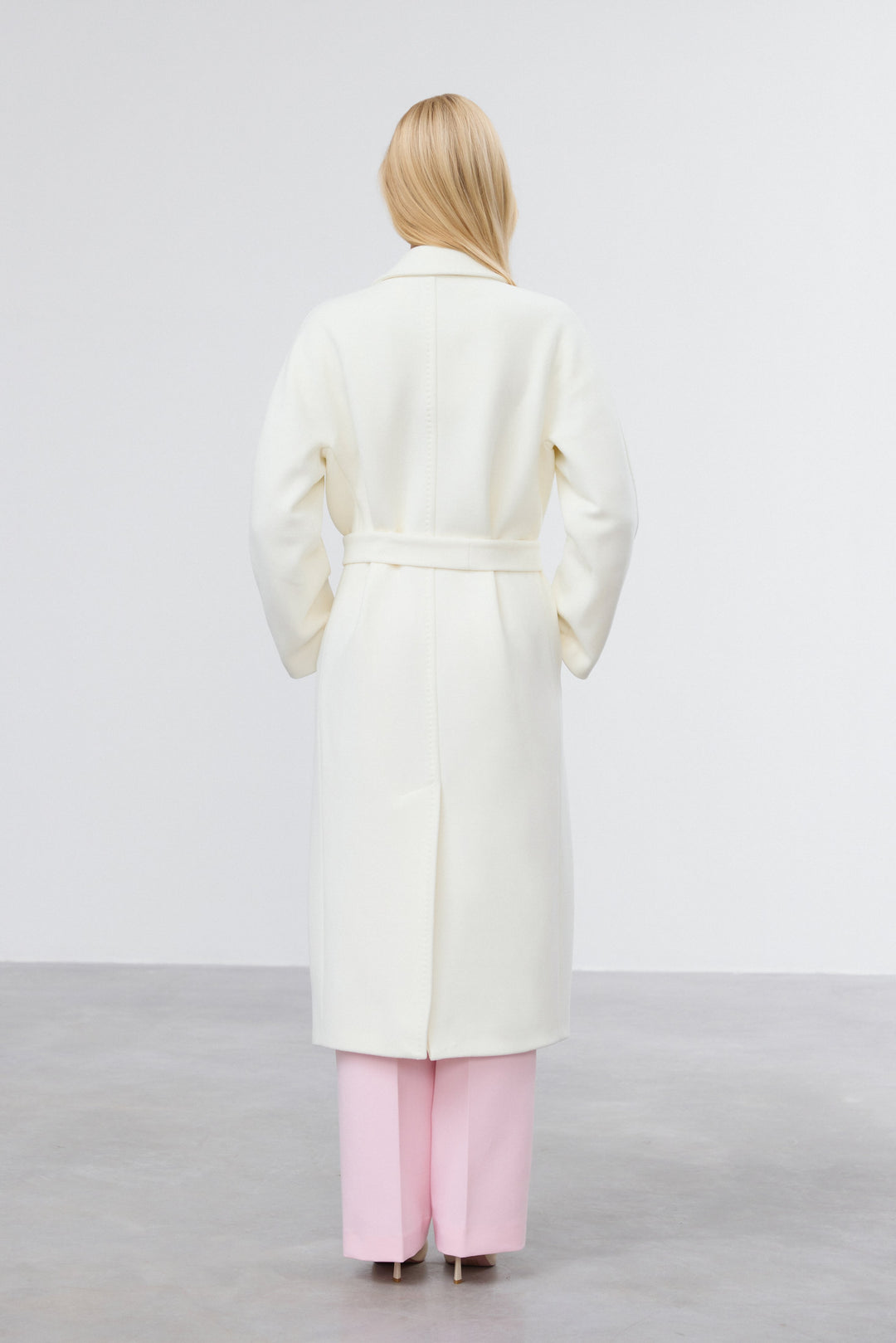 Back view of milky beige belted bucket coat.