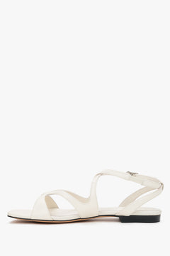 Side view of women’s milky beige flat sandals.