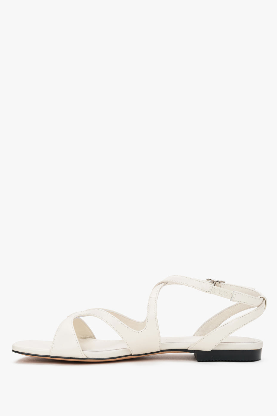 Side view of women’s milky beige flat sandals.