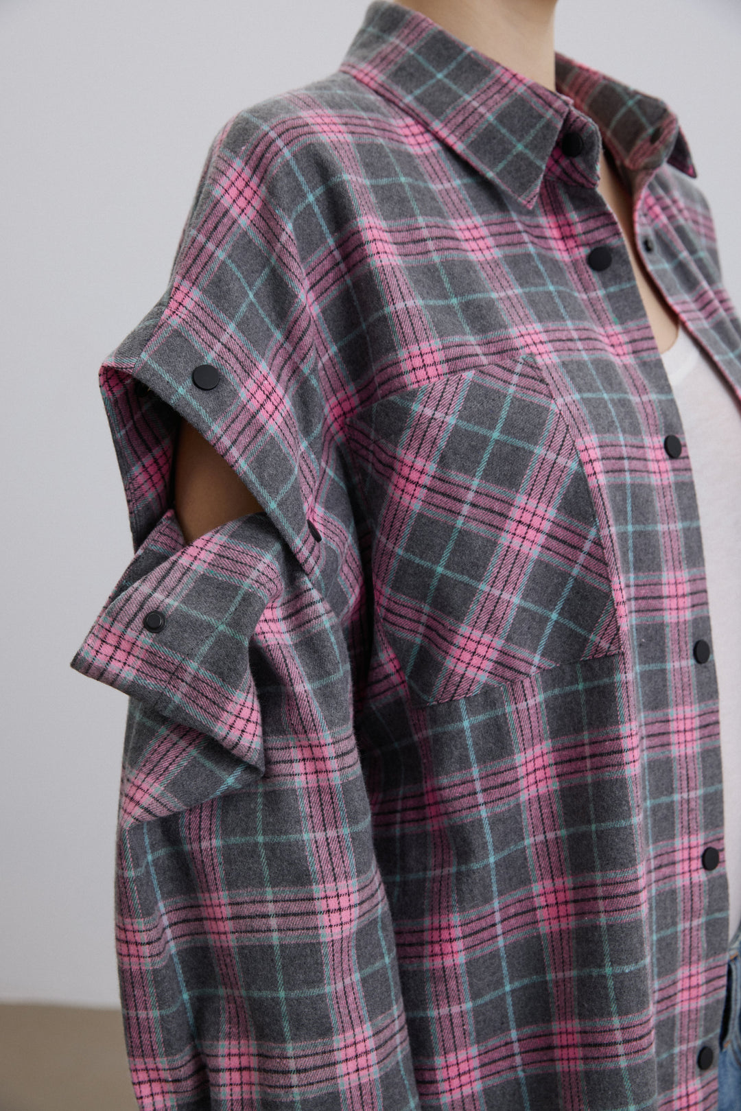Close-up of buttons for detachable sleeves on pink-grey shirt.