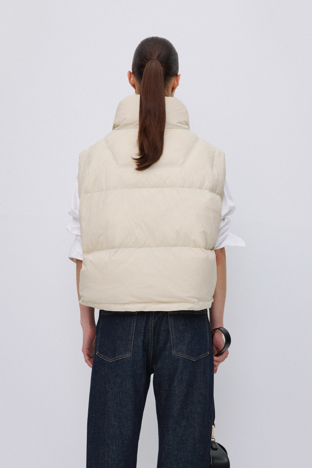 Back of women's short light beige down vest.