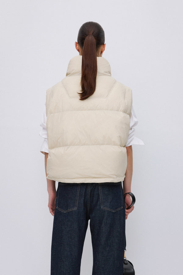 Back of women's short light beige down vest.