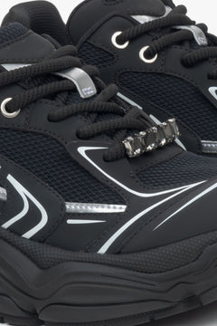 Black women's sneakers with rhinestones on the laces – close-up of the lacing system.