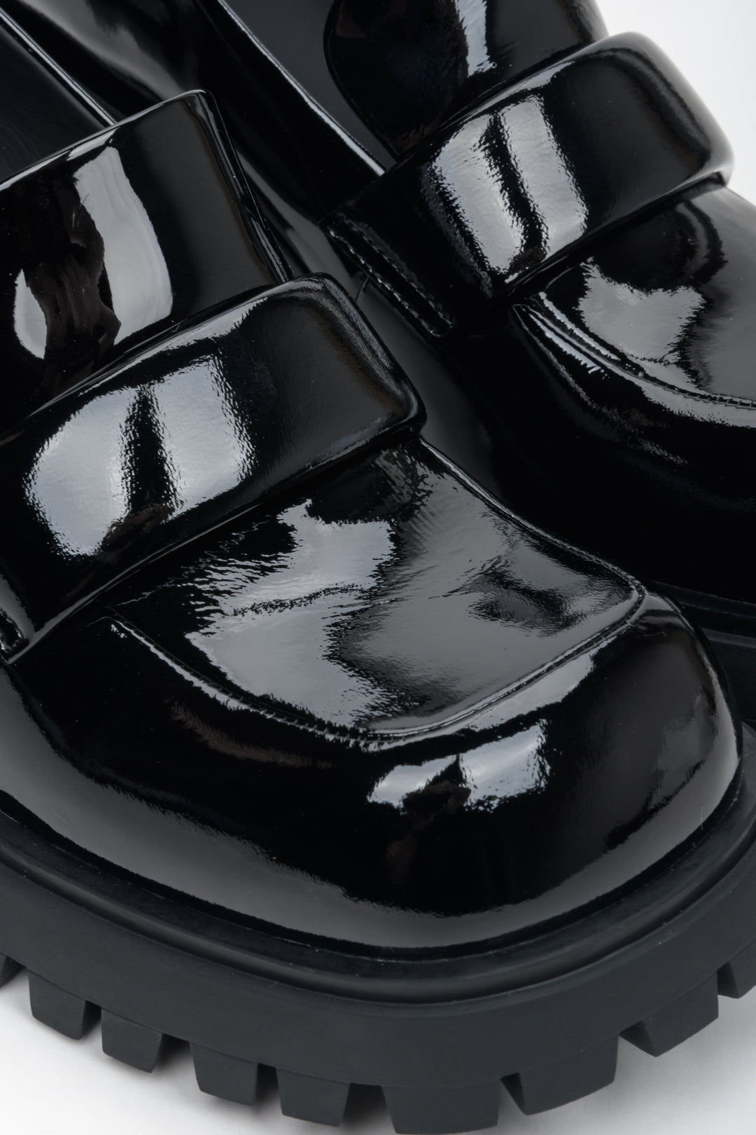 Women's black heeled loafers made of genuine patent leather - close-up on details.