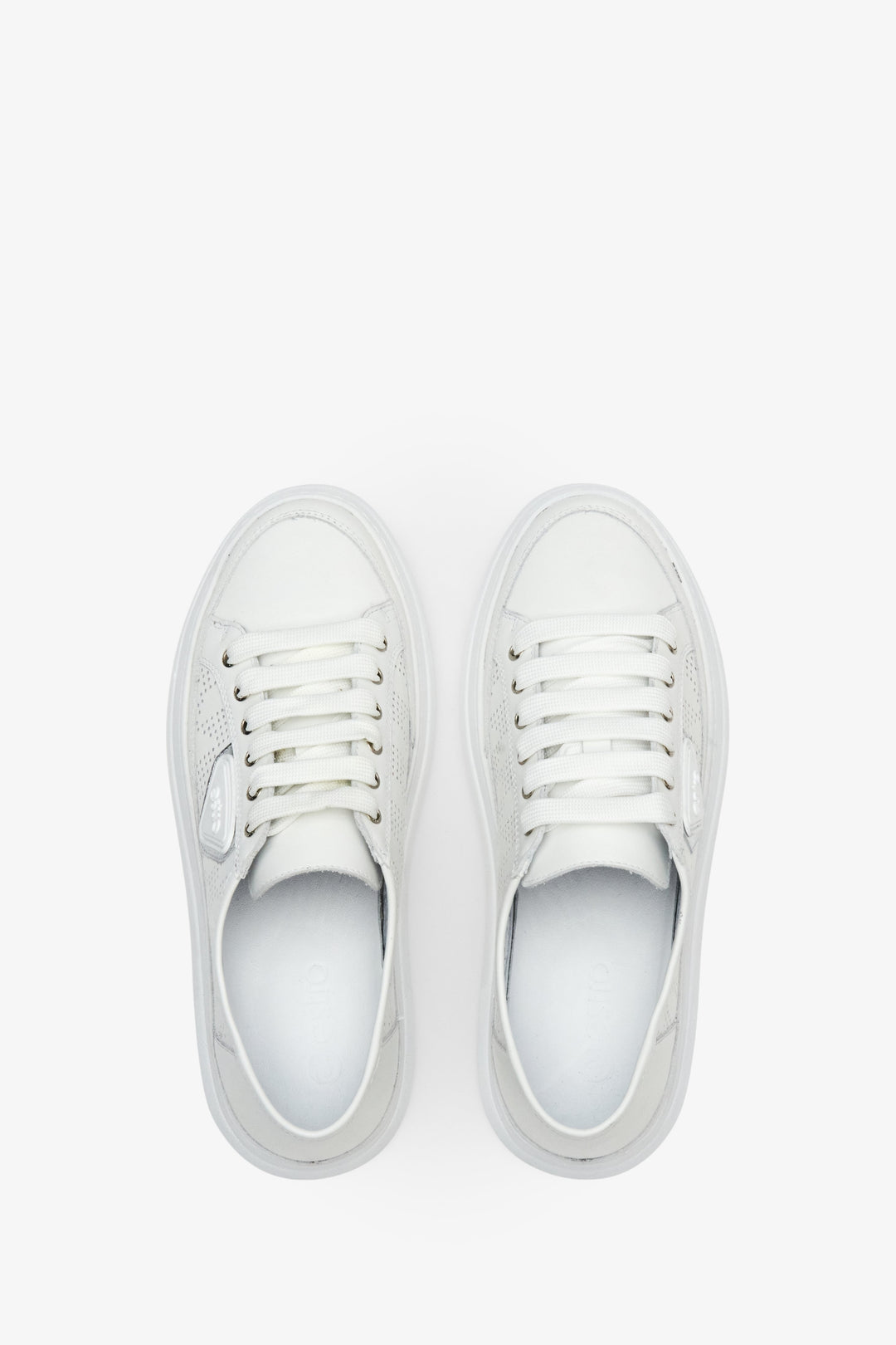 Women's white leather sneakers with laces - presentation of the footwear from the top.