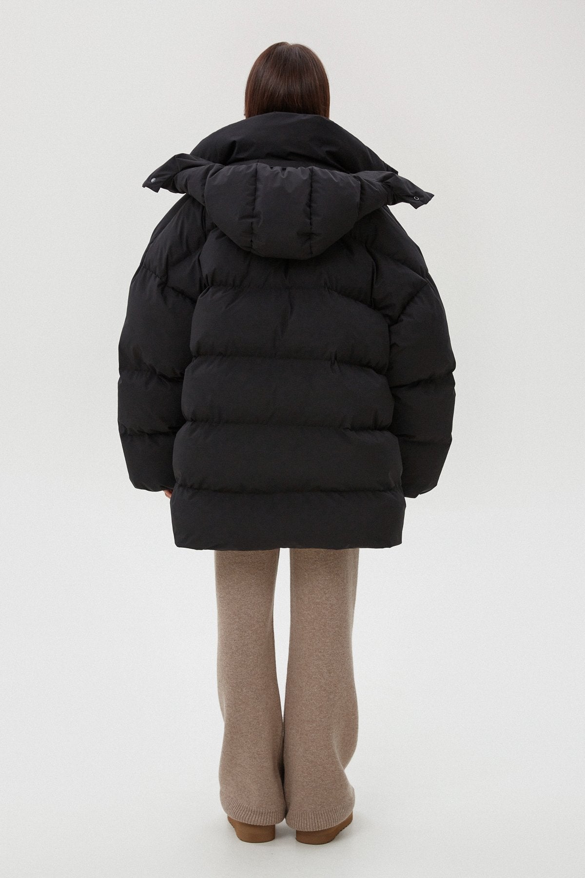 Women's black puffer jacket by Estro - back view of the model.