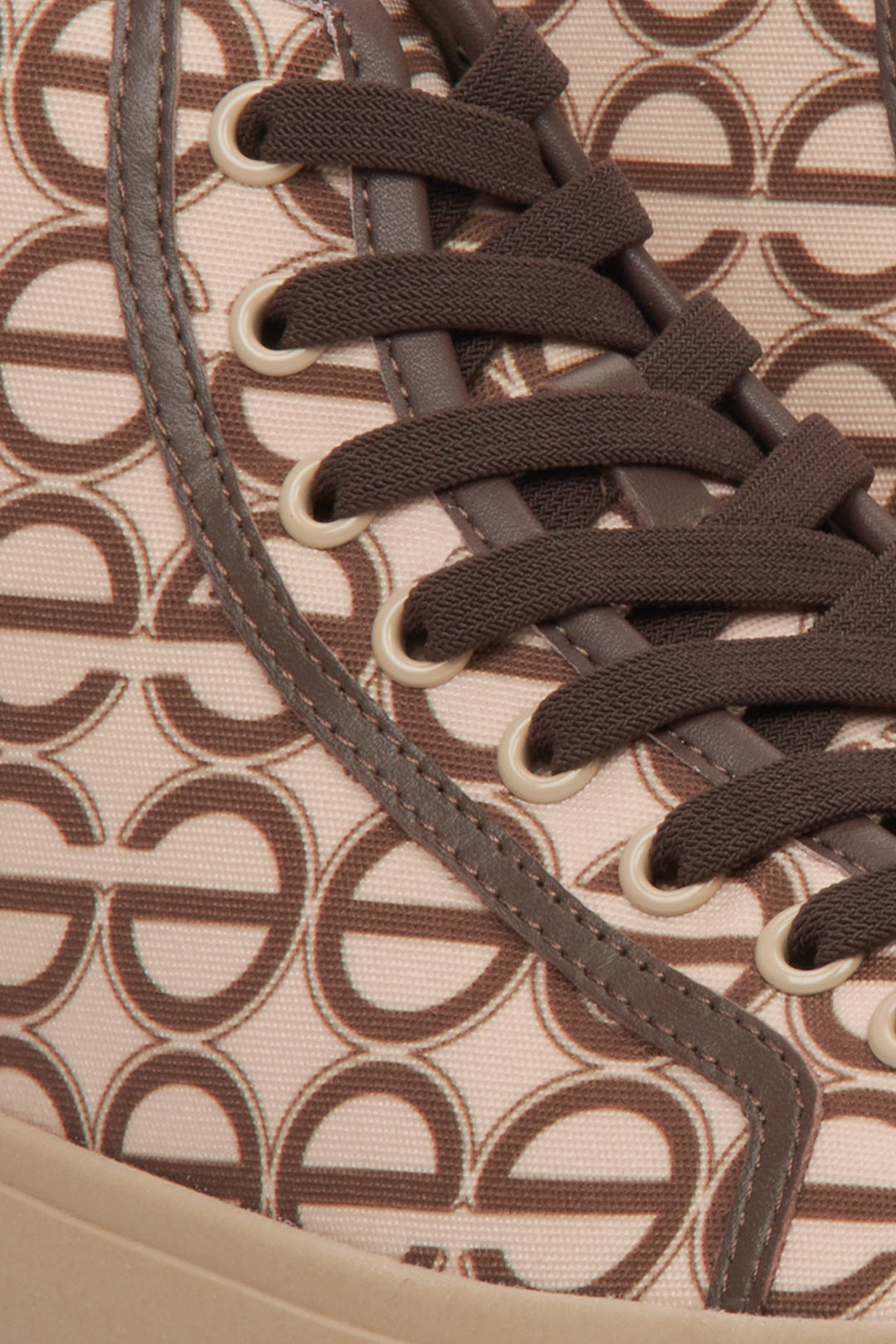 Sporty women's sneakers in beige and brown, laced - a close-up on details.